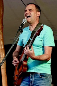 a man singing into a microphone while playing an electric guitar