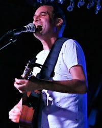 a man singing into a microphone while playing an acoustic guitar
